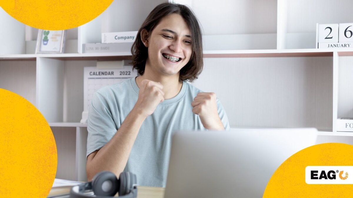jovem sorrindo e feliz após ver em seu notebook que suas metas foram atingidas