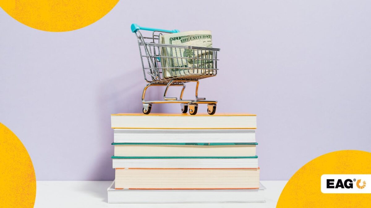 maço de dinheiro dentro de um carrinho de compras sobre uma pilha de livros||||