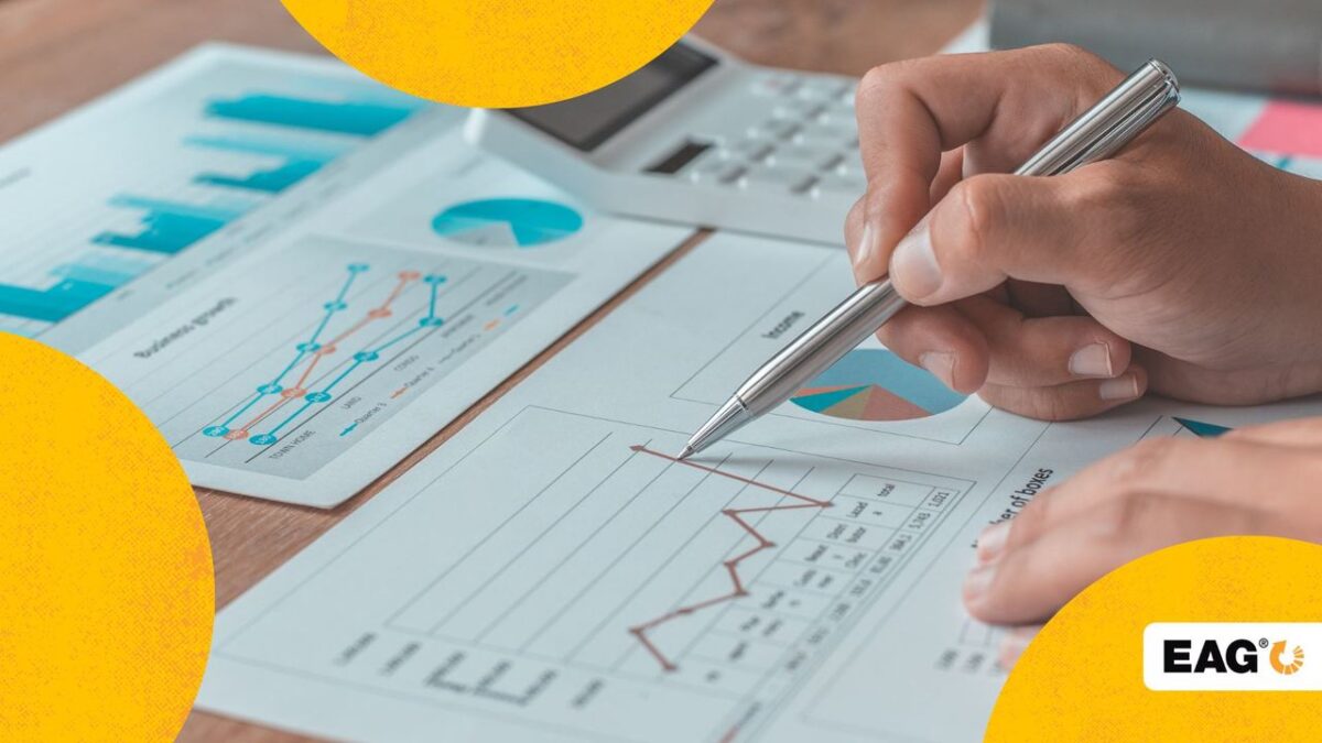 pessoa com uma caneta na mão analisando uma folha com gráficos de crescimento do seu negócio